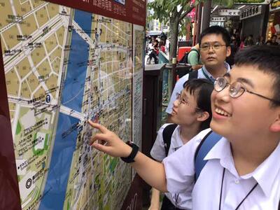 歩道の案内板に掲げられた周辺地図を見ている二人。「ここは、どこかな?」 歩道の案内板に掲げられた周辺地図を見ている二人。「ここは、どこかな?」
