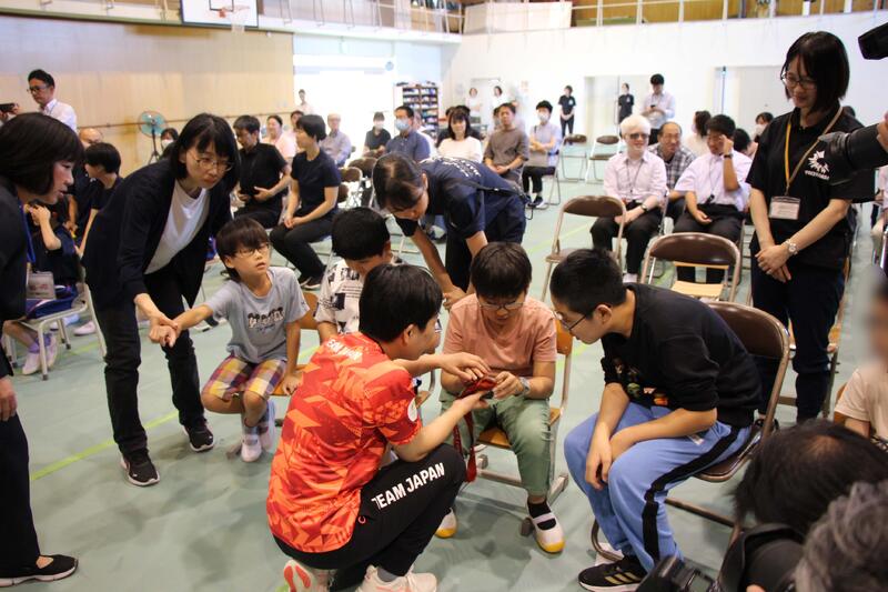 半谷選手とメダルに触る生徒 半谷選手とメダルに触る生徒