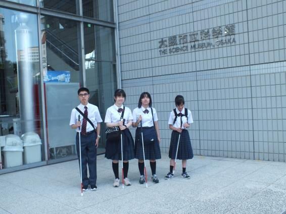 玄関前で記念撮影する生徒４名